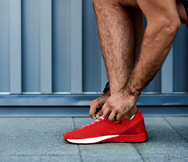 Športovec si zaväzuje šnúrky na červených topánkach